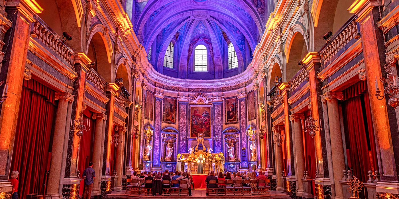 Guests watching a performance, surrounded by the stunning baroque interior of the Trinity Chapel in Lyon.