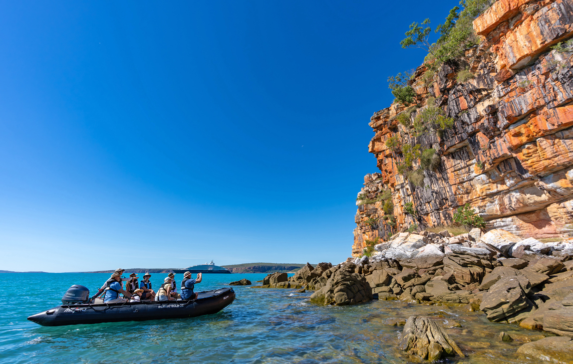 Group in Zodiac taking photos of wildlife on rock coastline